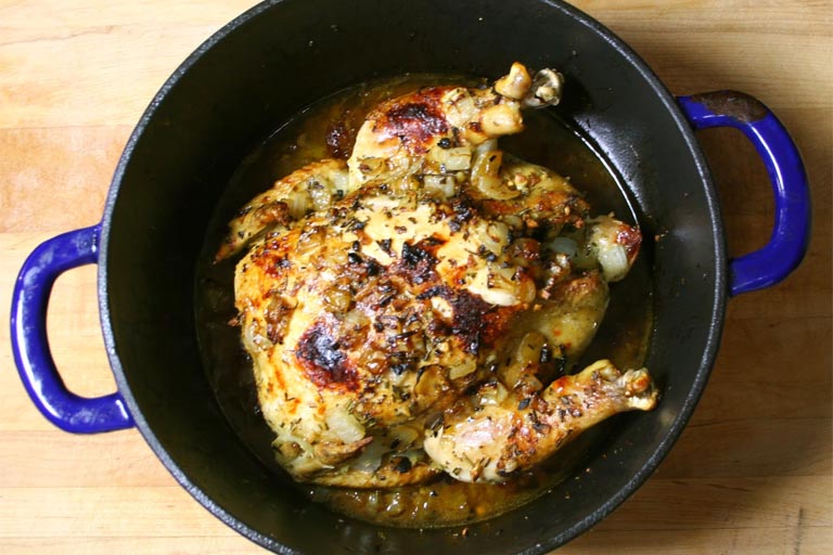 chicken being roasted in dutch pan